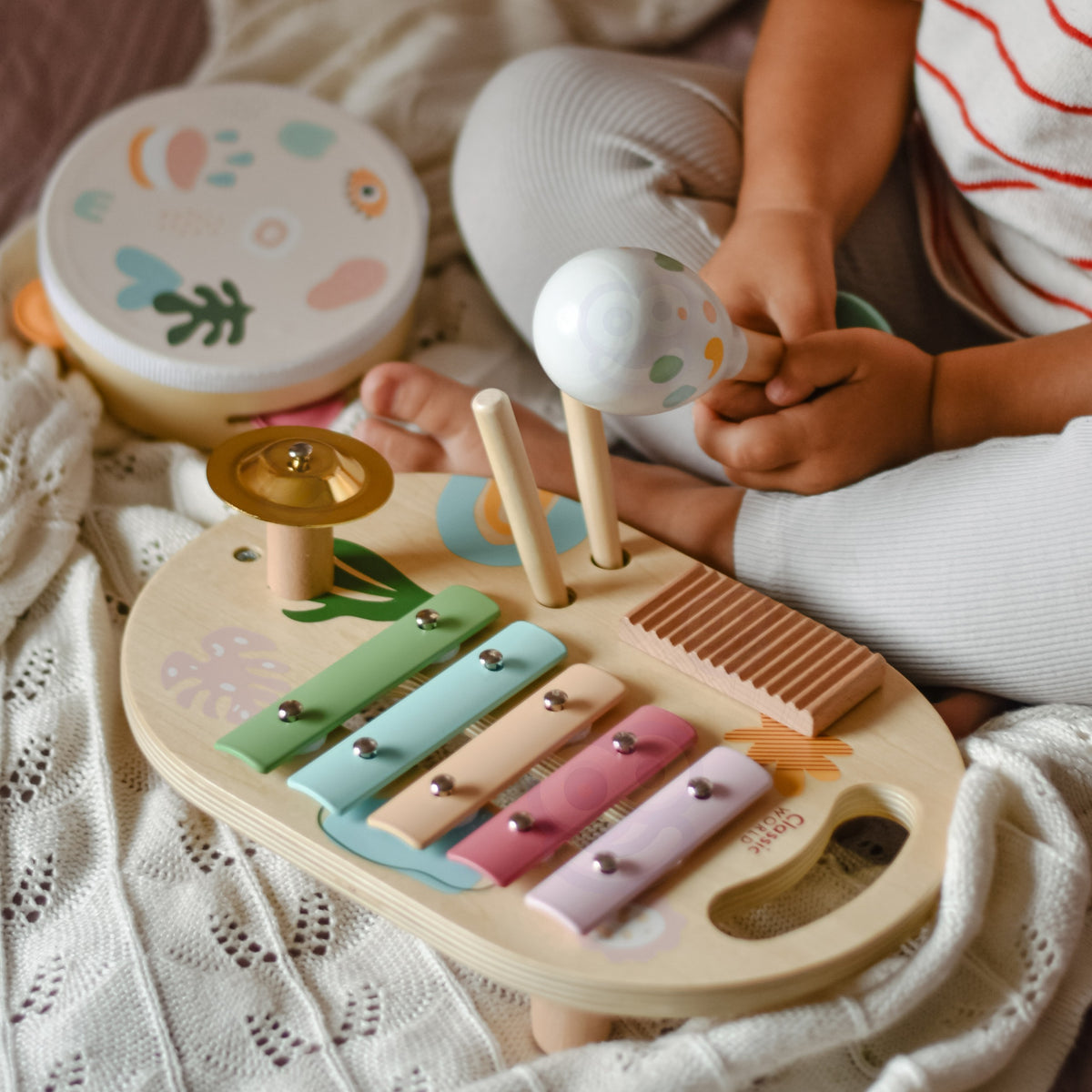 Toddler playing the wooden xylophone with drumsticks