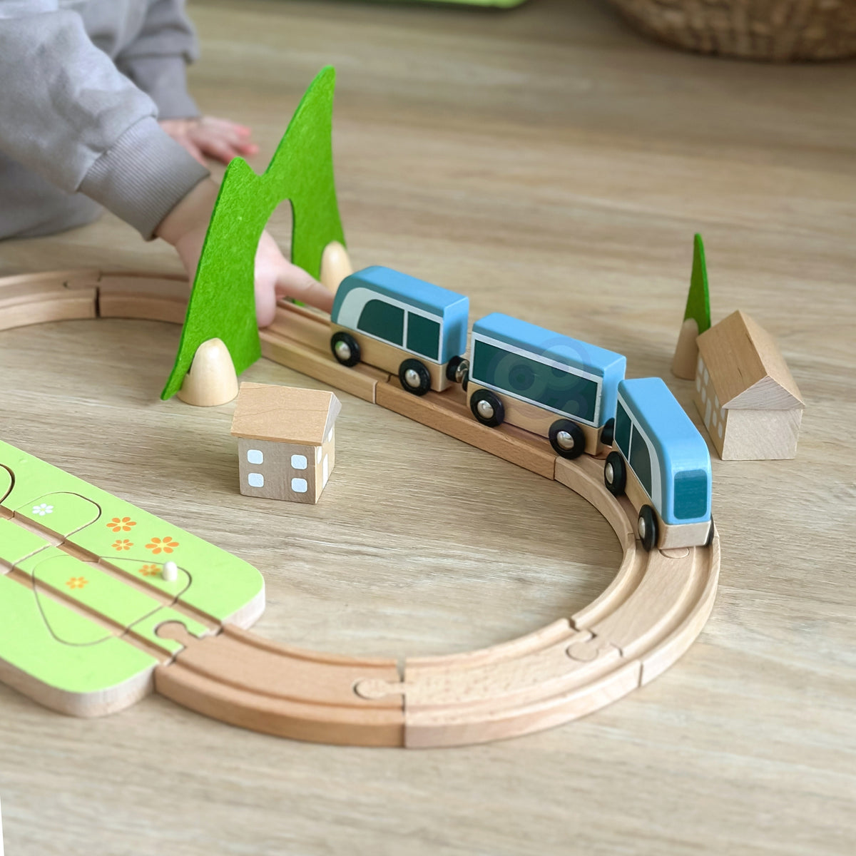 Child building the wooden train track with a station