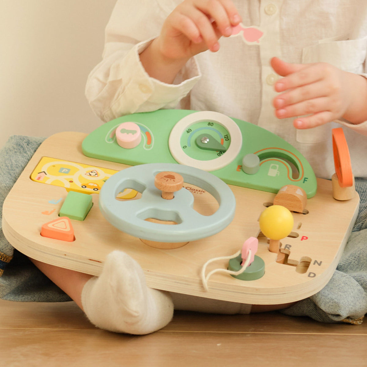 Toddler playing driver with the wooden steering board