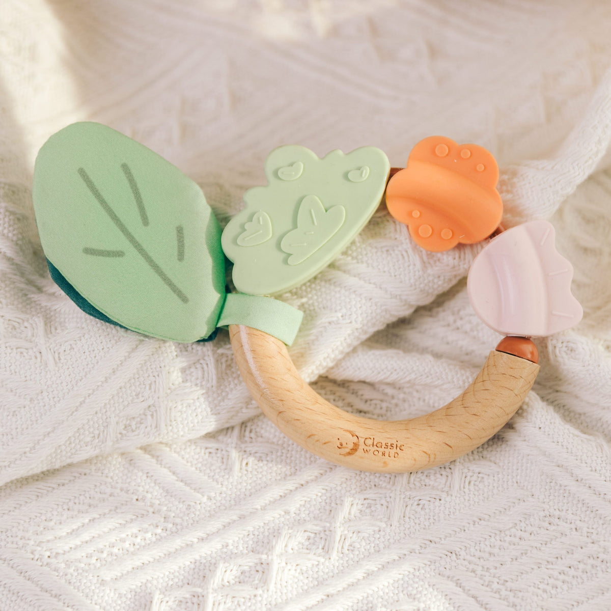 Baby holding and chewing the wooden sensory teether