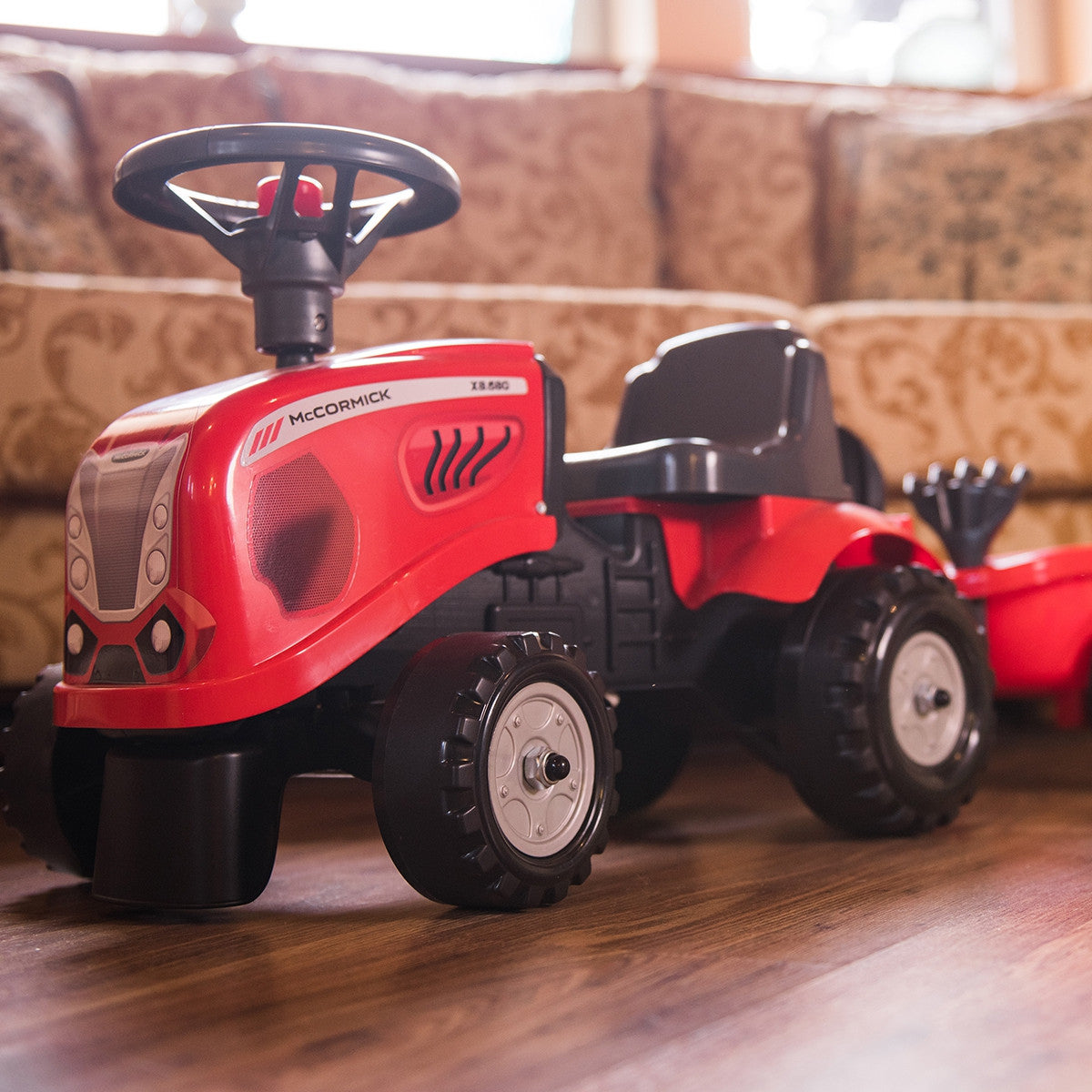 Red McCormick tractor with shovel and rake in the trailer