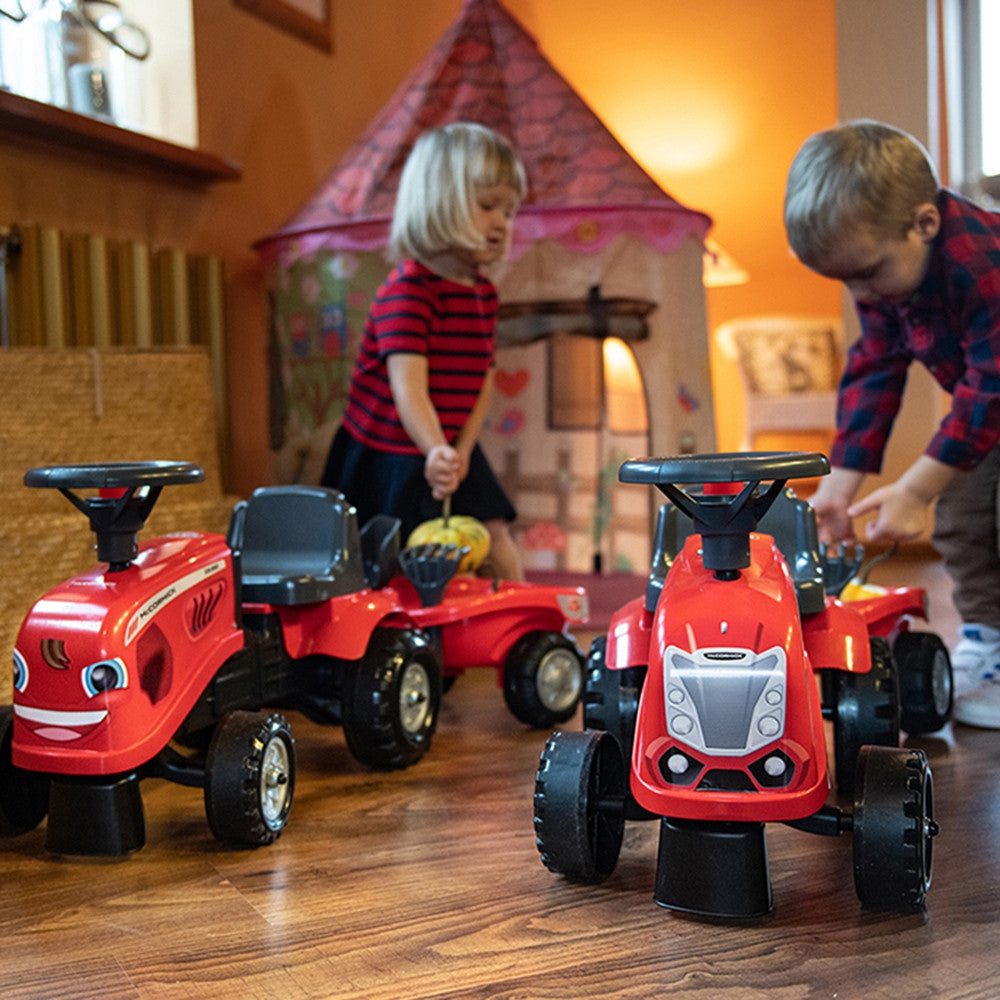 Toddler riding the red McCormick tractor outdoors