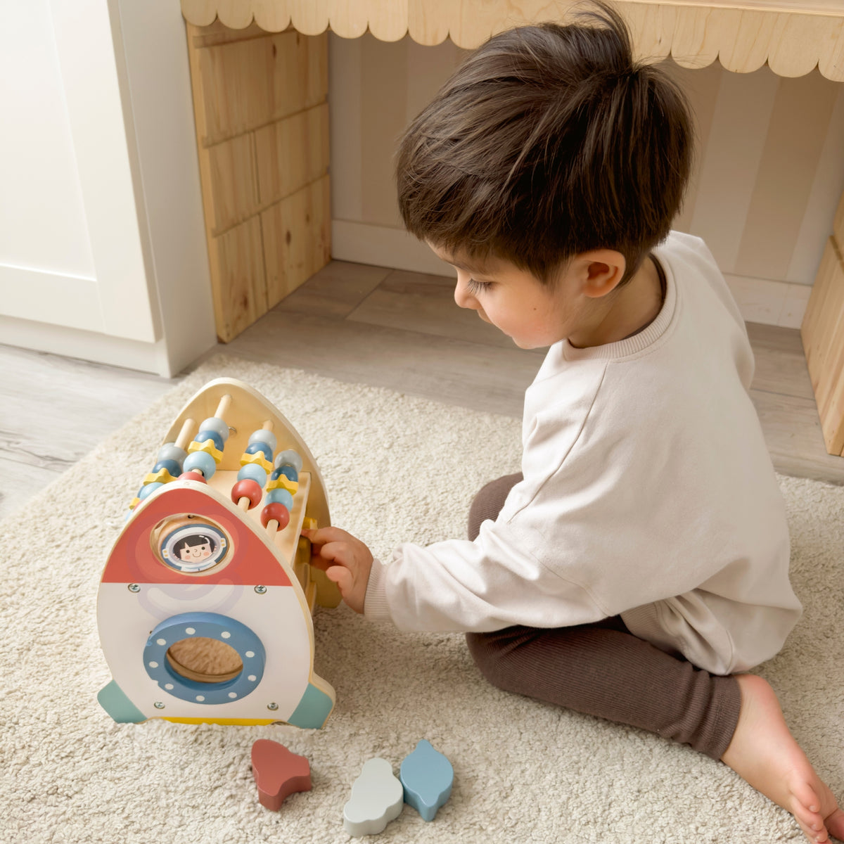 Toddler sorting shapes into the wooden rocket