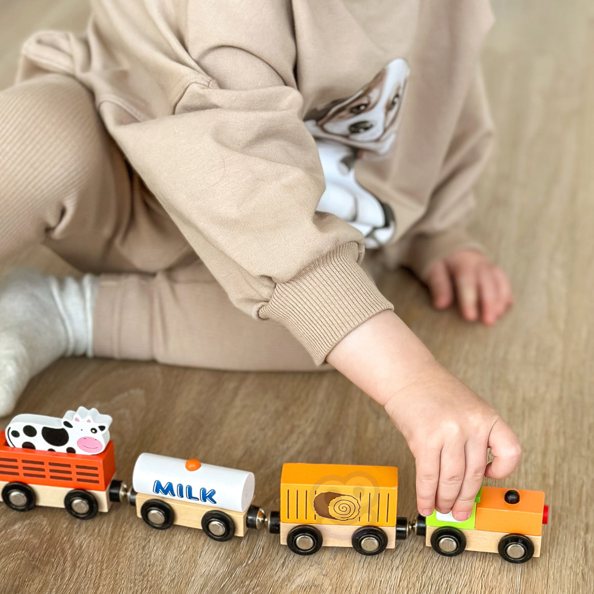 Wooden locomotive pulling a wagon with a cow figure