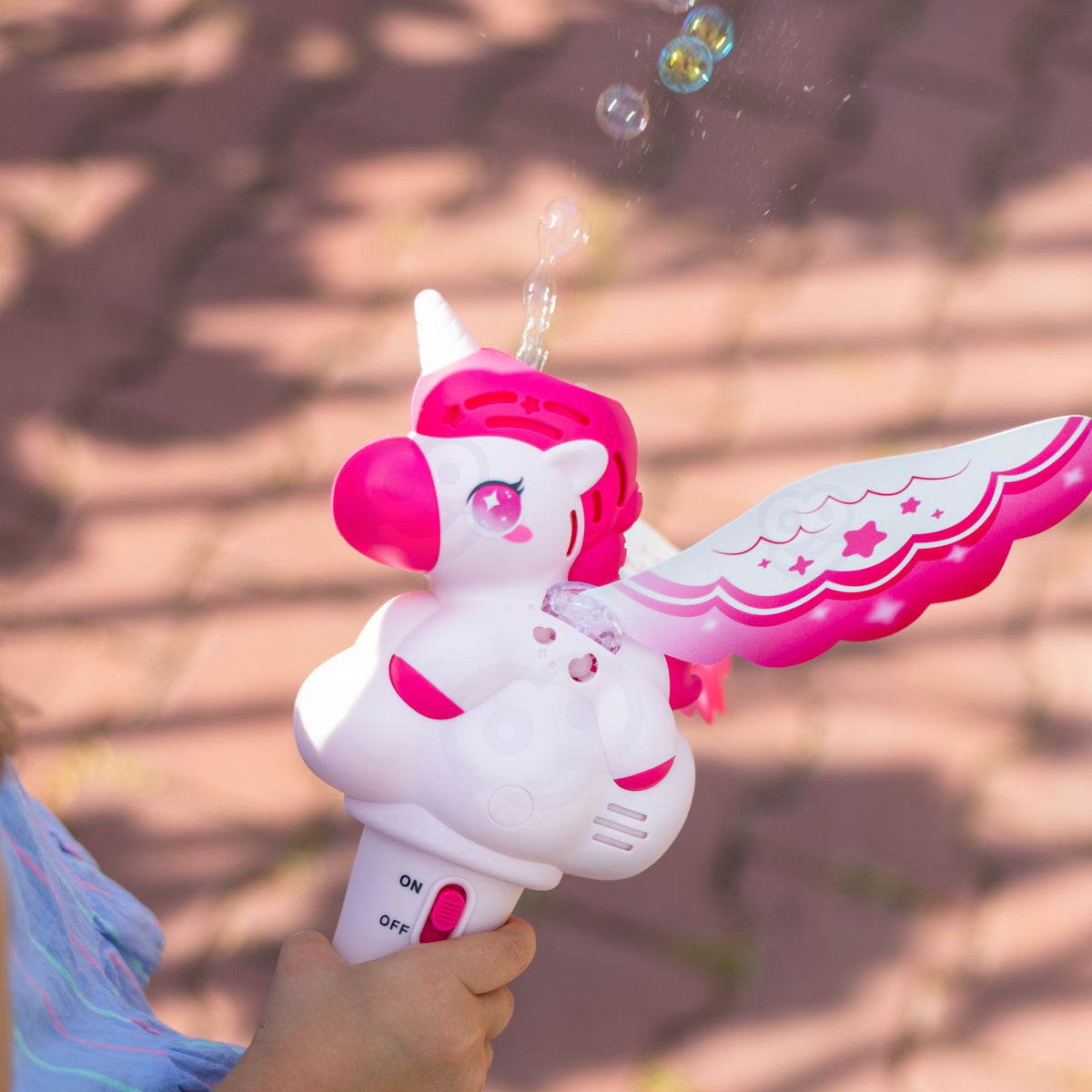 Child running with the unicorn bubble wand outdoors