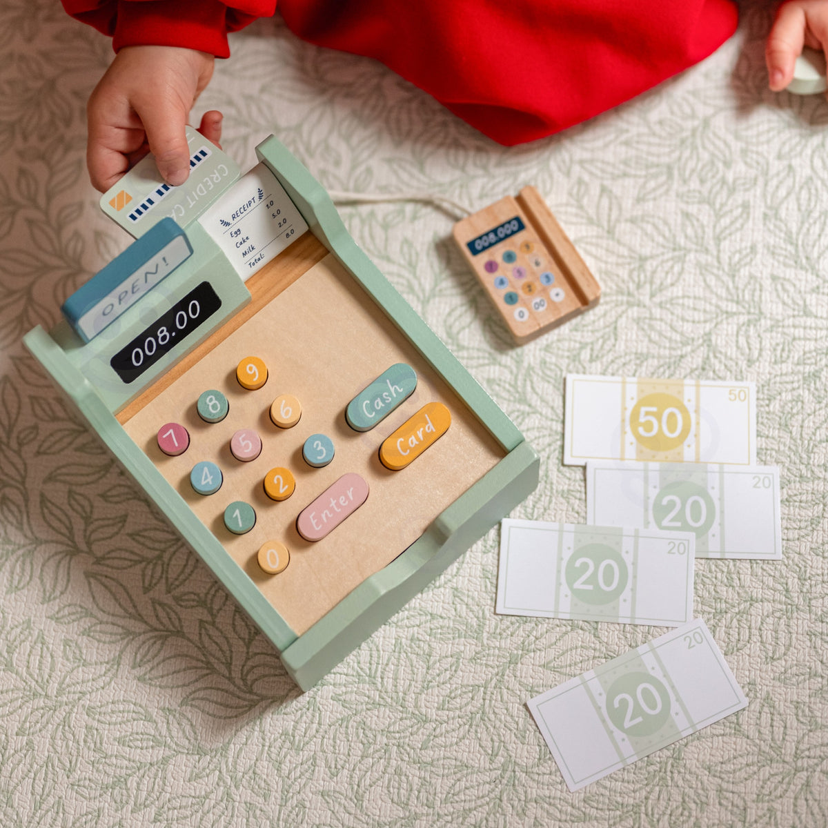 Child playing shop with the wooden cash register