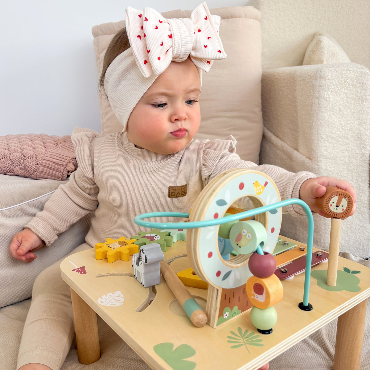 Toddler sliding beads on the activity table